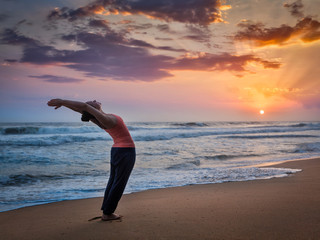 Fototapeta na wymiar Young sporty fit woman doing yoga Surya Namaskar