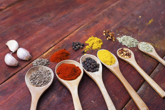 Wooden spoons full of aromatic herbs and spices on a rustic wooden cutting board