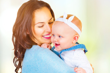 Happy family. Mom and baby girl kissing and hugging at home
