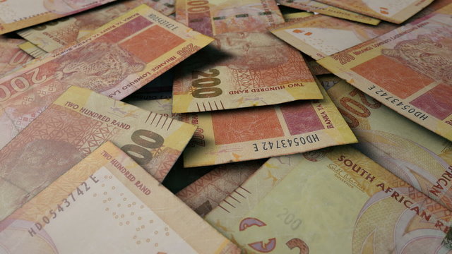 An extreme close up pan of a pile of randomly scattered south african rand banknotes