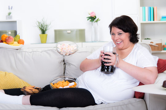 Übergewichtige Frau trinkt und isst Ungesundes