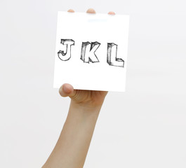 Hand holding a piece of paper with sketchy capital letter s J K L, isolated on white.