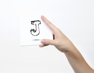 Hand holding a piece of paper with sketchy capital letter J, isolated on white.