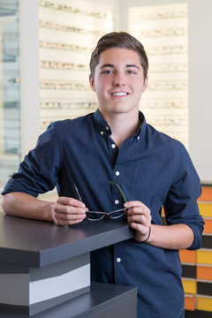 Junger freundlich l&auml;chelnder Mann beim Optiker