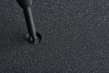 screwdriver and screw on a laptop