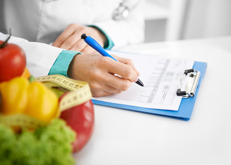 Doctor nutritionist writing case history in the office. Young woman dietitian prescribing recipe.  - 94716982