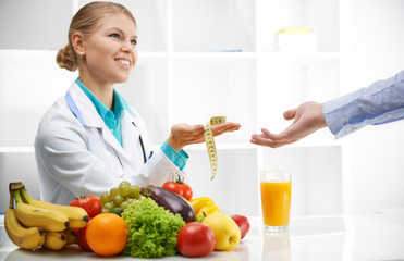 Portrait of smiling female dietitian giving measuring tape to patient. Slimming concept.