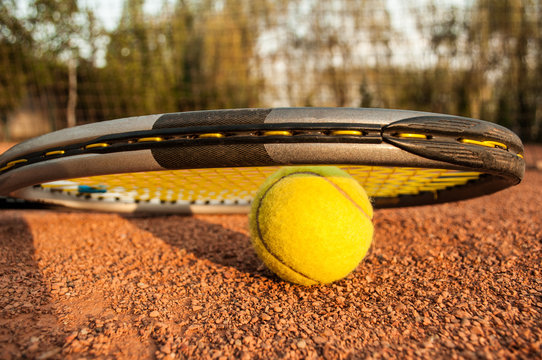 Tennis concept with racket and ball on clay at sunset