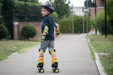 Young boy having fun on roller skates outdoors in summer time.