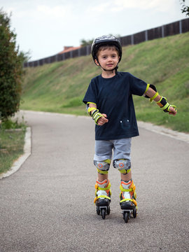 Young boy having fun on roller skates outdoors in summer time.