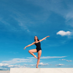 Fototapeta premium Young beautiful ballerina dancing outdoors in a modern environme