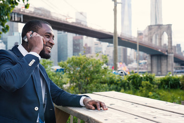 Smiling young businessman talking at the phone. Brooklyn Bridge. New York City.