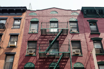 Facade of an old red brick apartment building in Little Italy, New York City.