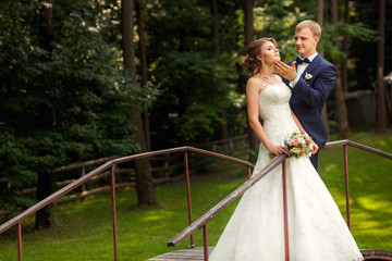 Bride and groom on bridge in forest