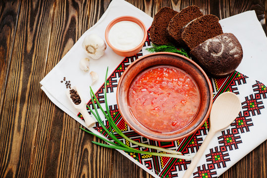 
Ukrainian national cuisine , red borscht with sour cream , herbs , garlic and rye bread on a wooden background