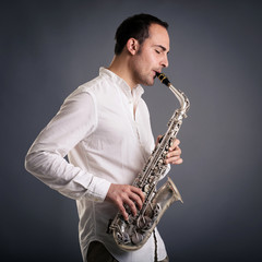 Fototapeta na wymiar Saxophone player man isolated against dark background. Close up
