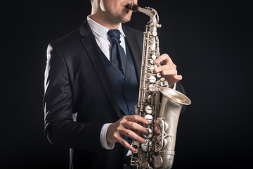 Saxophone player man isolated against black background. Close up - obrazy, fototapety, plakaty