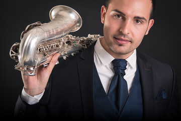 Confident saxophonist man isolated against black background. Clo