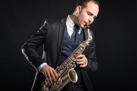 Saxophone player man isolated against black background. Close up