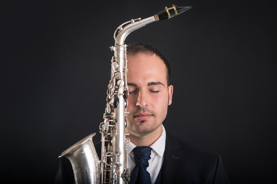 Saxophonist man with closed eyes isolated against black backgrou