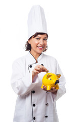 portrait of a mature woman wearing like a chef putting coins into the moneybox on a white background