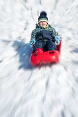 Fototapeta na wymiar Young kid sliding with bob in the snow. Image edited with radial