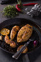 Chicken breast in a cooking pan, on a kitchen board.