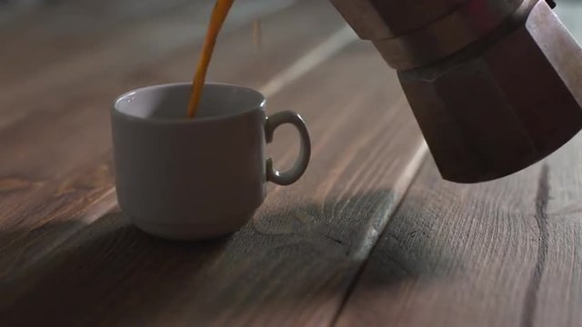 pours hot coffee into a cup