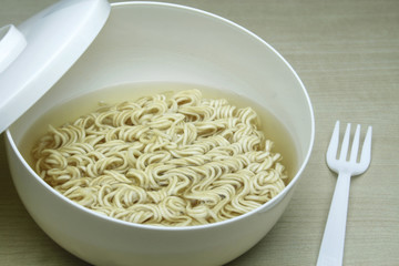 Instant noodles in white dish on wood background