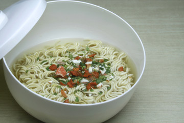 Instant noodles in white dish on wood background