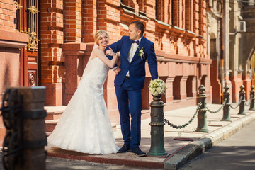 Bride arm in arm with groom near fashionable building