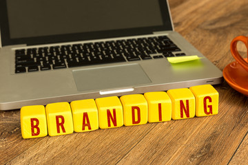 Branding written on a wooden cube in front of a laptop
