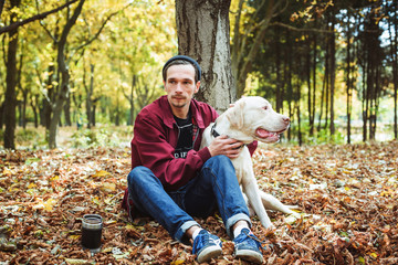 Fototapeta premium man drinking coffee in park and playing with labrador dog