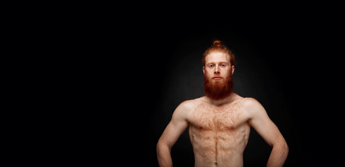 Portrait of muscular bearded man isolated on black background.
