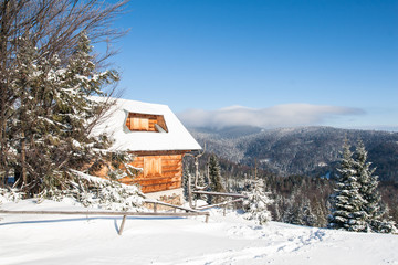 Zasypana śniegiem chata w górskim lesie z pięknym widokiem - obrazy, fototapety, plakaty