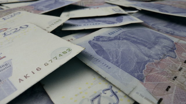 An extreme close up pan of a pile of randomly scattered british pound banknotes