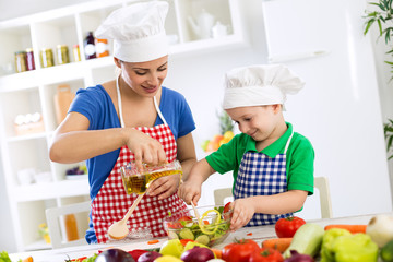 Mother and child putting olive oil to vegetables lettuce