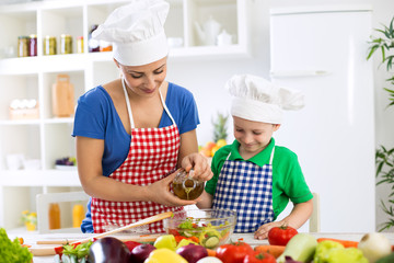 Mother and child putting olive oil to vegetables lettuce