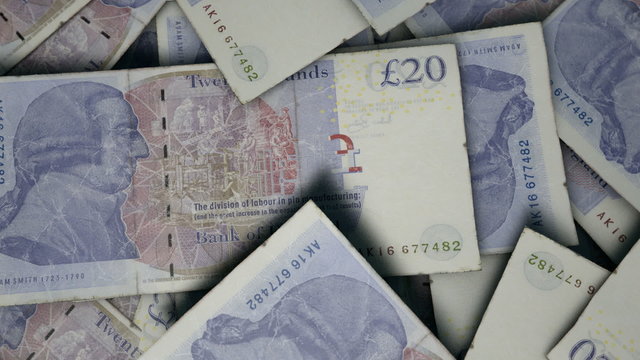 An extreme close up pan of a pile of randomly scattered british pound banknotes