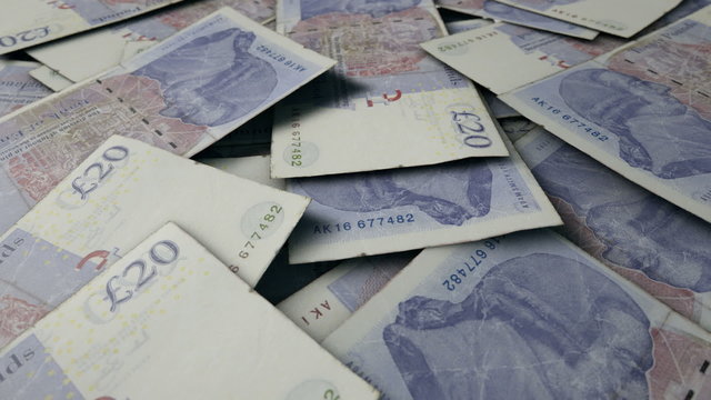 An extreme close up pan of a pile of randomly scattered british pound banknotes