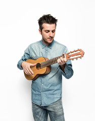 Obraz premium Musico tocando una guitarra pequeña sobre fondo blanco