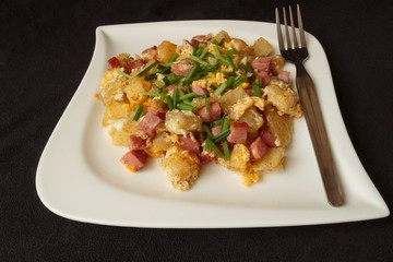 scrambled eggs served with pieces of sausage on a white plate