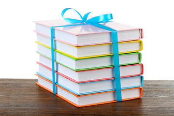 Stack of books with ribbon on light background