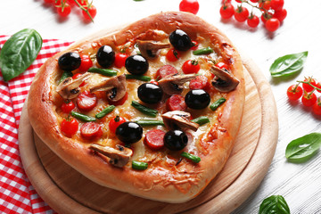 Heart shaped tasty pizza and red checked cotton serviette on wooden background