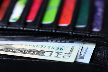 Black leather wallet with colourful credit cards and money, close up