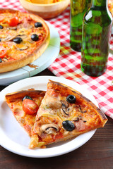 Sliced pizza served with beer on wooden table