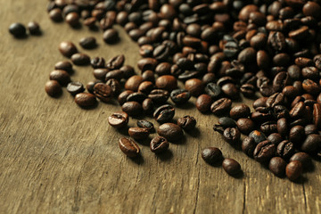 Aromatic coffee beans scattered on wooden background