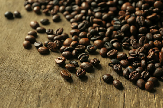 Aromatic coffee beans scattered on wooden background © Africa Studio