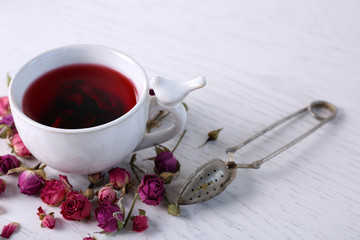 Tea and tea rose flowers on table closeup
