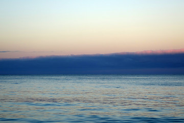 Fototapeta premium Calm ocean waters of Waimanalo Bay at dusk with clouds hanging o